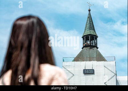 Deggendorf, Deutschland. 11 Juni, 2019. Eine Frau schaut sich eine digitale Zeitanzeige auf dem Rathausturm. Da das Alte Rathaus eingeschlossen war, die Uhr der Turm hat auch versteckt. Bis voraussichtlich Mitte Juli, zwei LED-Panels über dem Gerüst wird die Zeit angezeigt. Foto: Armin Weigel/dpa/Alamy leben Nachrichten Stockfoto