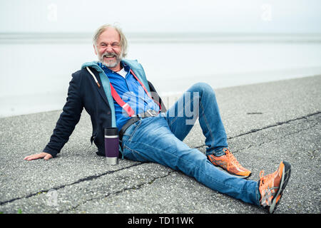 Norddeich, Deutschland. 11 Juni, 2019. Klaus-Peter Wolf (Autor) sitzt auf dem Deich. Der vierte Film im Ostfriesland Kriminalität Serie basiert auf dem gleichnamigen Roman von Klaus-Peter Wolf (über die dpa erfolgreicher Autor Klaus-Peter Wolf bietet Material für neuen ZDF-Krimi'). Credit: mohssen Assanimoghaddam/dpa/Alamy leben Nachrichten Stockfoto