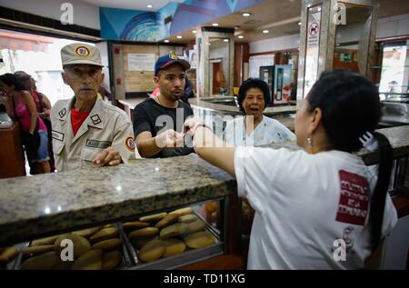 05. Juni 2019, Venezuela, Caracas: Menschen kaufen Brot im 'La Minka, eine Bäckerei, die von Anhängern der Regierung. Die ehemalige private Bäckerei war 'Mansion Bäckerei' genannt. Jetzt rund 6.000 Stücke Brot gibt es jeden Tag bei der Preise durch den Staat produziert. Das Land mit den größten Ölreserven der Welt befindet sich in einem dramatischen Niedergang. Geld Abwertung ist die höchste in der Welt, für viele Menschen essen ist unbezahlbar. Diese 'Bäckereien Bolivarischen', das Brot zu festen Preisen verkaufen, sehen ihre Aufgabe als Teil der "Sozialismus des 21. Jahrhunderts" ausgerufen, die von der späten Staatschef Hugo Chavez. Foto: Stockfoto