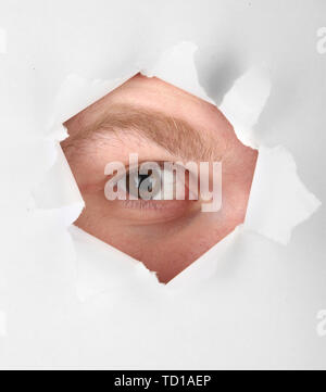 Mann Auge durch das Loch im Blatt Papier Stockfoto