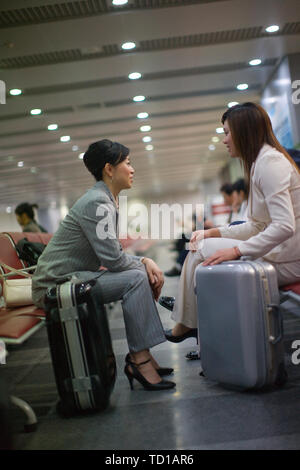 Junge Erwachsene business Frauen in einem Wartezimmer sitzen mit Koffern. Stockfoto