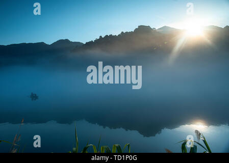 Nebel füllt Xiao Dongjiang 3 (Am frühen Morgen des Sommers, dicker Nebel durchdringt Xiao Dongjiang und in der Licht und Schatten auf den Sonnenaufgang, Fischer bereiten Sie Fisch.) Stockfoto