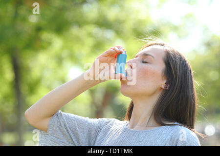 Die Frau ist mit einem Asthma Inhalator im Freien in einem grünen Park Stockfoto