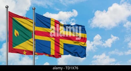 Grenada und Aland Inseln Flagge im Wind gegen Weiße bewölkt blauer Himmel zusammen. Diplomatie Konzept, internationale Beziehungen. Stockfoto