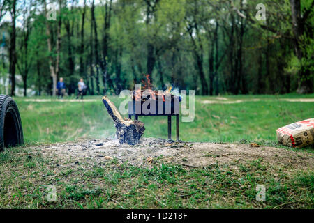 Im Park befindet sich ein Grill. Es brennt. In der Nähe von Menschen gehen. Stockfoto
