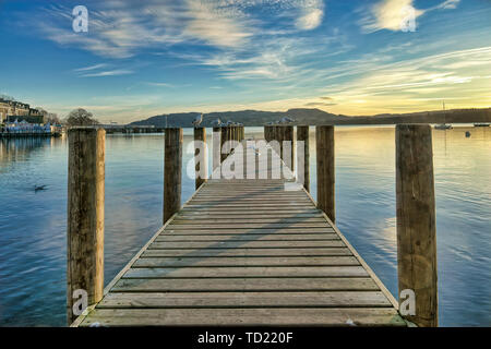 Ein Steg in einer ruhigen Windermere bei Sonnenuntergang. Stockfoto