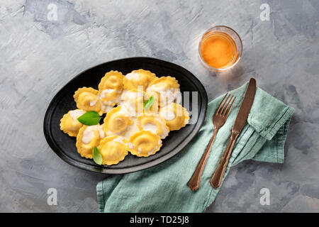 Eine Platte von Ravioli garniert mit frischem Basilikum Blätter, Schuß von der Oberseite mit einem Glas Weißwein und einen Platz für Text Stockfoto