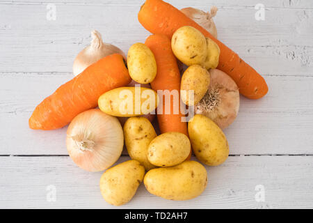 Sechs Goldene Schottischen gewachsen Zwiebeln 3 Karotten und Kartoffeln auf einem weißen Holz beplankt. Ein gutes Image für eine grüne Lebensmittelhändler oder Feinkost Stockfoto