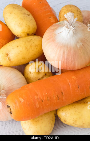 Sechs Goldene Schottischen gewachsen Zwiebeln 3 Karotten und Kartoffeln auf einem weißen Holz beplankt. Ein gutes Image für eine grüne Lebensmittelhändler oder Feinkost Stockfoto