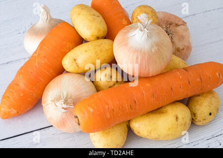 Sechs Goldene Schottischen gewachsen Zwiebeln 3 Karotten und Kartoffeln auf einem weißen Holz beplankt. Ein gutes Image für eine grüne Lebensmittelhändler oder Feinkost Stockfoto