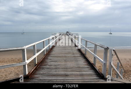 Tolle Aussicht von Hervey Bay aus der Holz- Torquay Jetty. Der Pier ist auch ein beliebter Angelplatz bei allen Gezeiten. Sprudeln Meer an einem bewölkten Tag. Horizontale Stockfoto