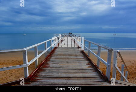 Tolle Aussicht von Hervey Bay aus der Holz- Torquay Jetty. Der Pier ist auch ein beliebter Angelplatz bei allen Gezeiten. Sprudeln Meer an einem bewölkten Tag. Horizontale Stockfoto