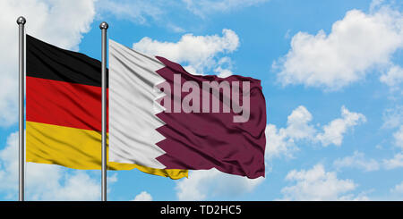 Deutschland und Katar Flagge im Wind gegen Weiße bewölkt blauer Himmel zusammen. Diplomatie Konzept, internationale Beziehungen. Stockfoto