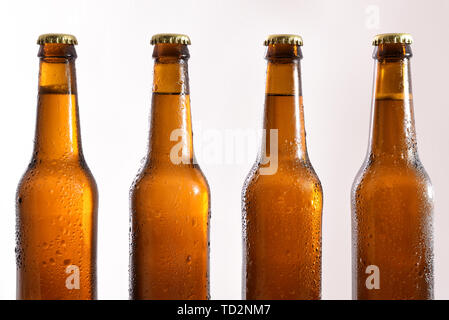 Reihe von vier geschlossenen Glas Flaschen mit frischem Bier auf weißem Hintergrund. Horizontale Komposition. Vorderansicht. Stockfoto