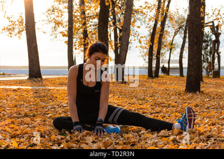 Chabarowsk, Russland - 07.Oktober 2018: Eine attraktive Frau im Sport Kleidung Sport übungen in der Natur gegen den Sonnenuntergang und den Amur, liebt Stockfoto