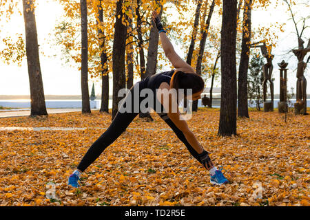 Chabarowsk, Russland - 07.Oktober 2018: Eine attraktive Frau im Sport Kleidung Sport übungen in der Natur gegen den Sonnenuntergang und den Amur, liebt Stockfoto