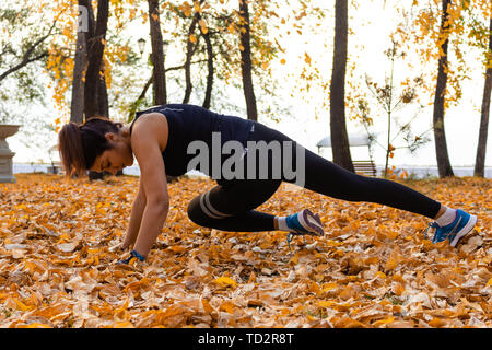 Chabarowsk, Russland - 07.Oktober 2018: Eine attraktive Frau im Sport Kleidung Sport übungen in der Natur gegen den Sonnenuntergang und den Amur, liebt Stockfoto