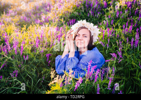 Hübsche Frau mit Blume Kranz in lila Feld. Portrait von Mädchen in Blau Stockfoto