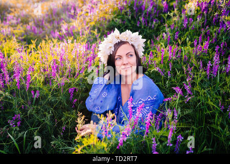 Hübsche Frau mit Blume Kranz in lila Feld. Portrait von Mädchen in Blau Stockfoto