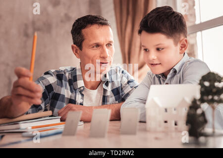 Wenig neugierig dunkelhaarige Junge Interaktion mit seinem Pflegevater Stockfoto