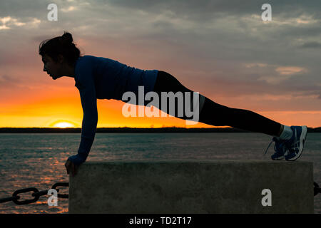 Chabarowsk, Russland - 07.Oktober 2018: Eine attraktive Frau im Sport Kleidung Sport übungen in der Natur gegen den Sonnenuntergang und den Amur, liebt Stockfoto