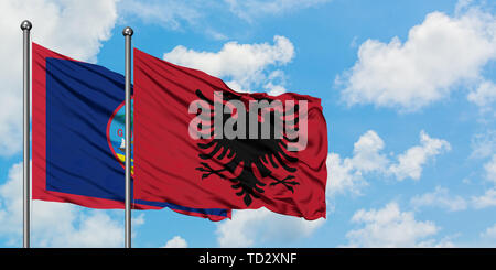 Guam und Albanien Flagge im Wind gegen Weiße bewölkt blauer Himmel zusammen. Diplomatie Konzept, internationale Beziehungen. Stockfoto