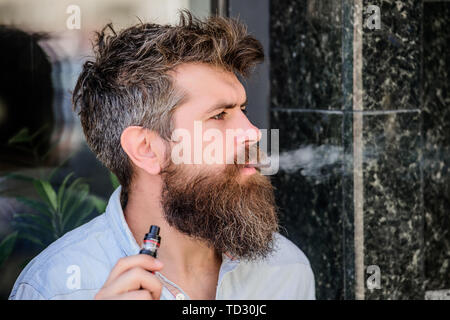 Bärtige brutalen Mann rauchen elektronische Zigarette. Reifen Hipster mit Bart. hipster Mann vaping Gerät. Mann rauchen ecigarette. Gesundheit, Sicherheit und Sucht. Dämpfe einatmen. Beleuchtung, Zigarette. Stockfoto