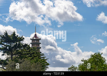Oben auf der großen Pagode über Bäume mit einem blauen und weißen bewölkten Himmel in Kew Gardens, London sichtbar. Stockfoto