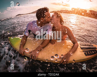 Happy romantisches Paar küssen beim Surfen im Meer - sportliches Surfer bodybording ein bewegender Moment im Wasser Stockfoto