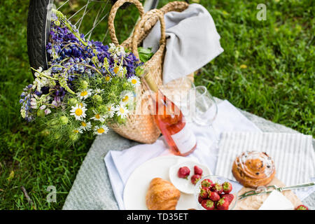 Schönen Sommer Picknick mit Erdbeeren, Käse und Wein auf der Wiese im Stadtpark, im Freien Abendessen Dekoration Stockfoto