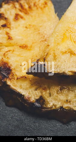 Gegrillte Ananasscheiben schließen bis auf schwarzem Hintergrund Stockfoto