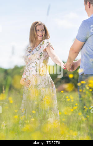 Junge glücklich schwanger Paar in Liebe Hände halten, entspannen in der Wiese. Stockfoto