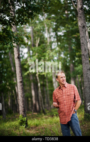 Reifer Mann nimmt einen Bruch auf einem Spaziergang durch den Wald, die Schönheit der Natur zu bewundern. Stockfoto