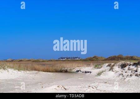 Panoramablick über das Gras bedeckt Sand an den Gebäudekomplex in der Ferne. Blick vom wunderschönen Strand der Nordsee in Sankt Peter-Ording Stockfoto