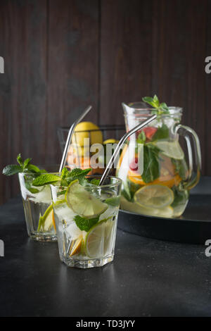 Detox Limonade mit Limone, Orange, Zitrone, Erdbeere in Glas und Glas. Sommer gesunde frische Getränk. Dunklen Hintergrund. Stockfoto