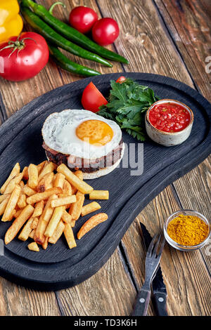 Rindersteak mit Ei und Salat aus grünen und Gemüse. Holz- Hintergrund, Tisch, Fine Dining Stockfoto