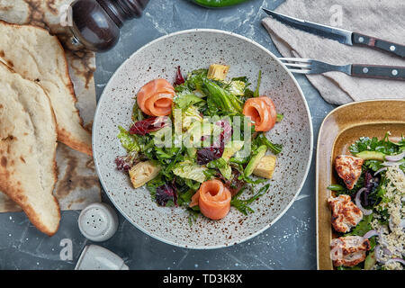 Essen Konzept, Tabelle mit verschiedenen Snacks platziert. Salat mit Lachs, Caesar skuric, eingelegte Pilze, Brot. Stockfoto