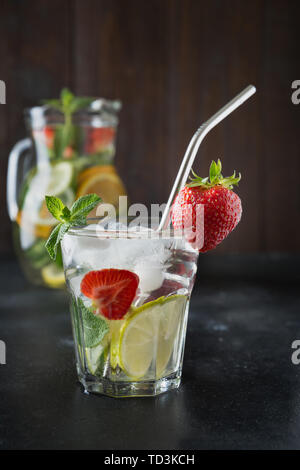 Detox Limonade mit Limone, Orange, Zitrone, Erdbeere in Glas und Krug. Sommer gesunde frische Getränk. Dunklen Hintergrund. Stockfoto