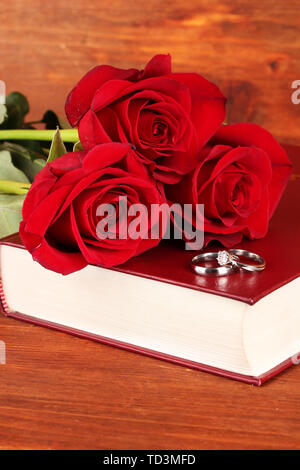 Trauringe auf Bibel mit Rosen auf Holz- Hintergrund Stockfoto