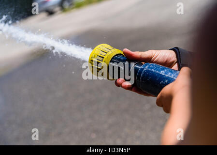 Hände von Feuerwehrmann, kein Gesicht, ein Schlauch durch das Werfen von Wasser unter hohem Druck. Stockfoto