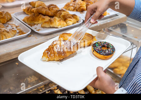 Nahaufnahme von Frau mit schelle Entnahme Croissant und Gebäck kaufen Stockfoto
