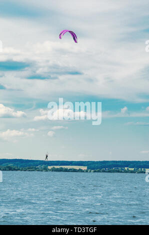 Ein kiteboarder ist über Wasser durch einen power Kite gezogen. Kitesurfer hoch im Flug Stockfoto