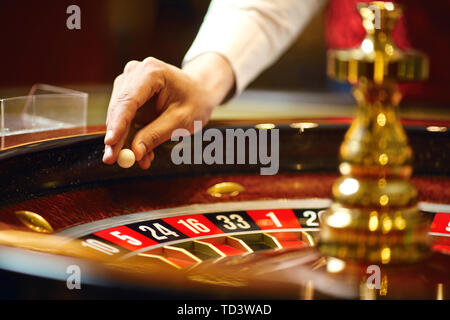 Der Croupier hält eine Kugel in einem Casino in seiner Hand. Das Spielen in einem Casino. Stockfoto