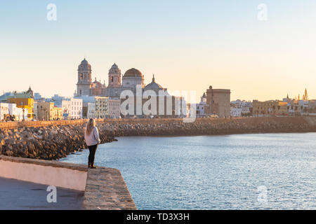 Frau genießen den Blick auf die Kathedrale von Santa Cruz und das Meer von der Promenade entlang Kai, Cadiz, Andalusien, Spanien, Europa Stockfoto