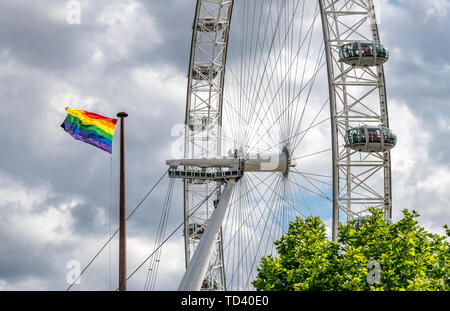 Gay Pride Regenbogen Flagge in London neben dem London Eye - Das Millennium Wheel. Das Rad ist jetzt von Coca Cola gesponsort. Stockfoto
