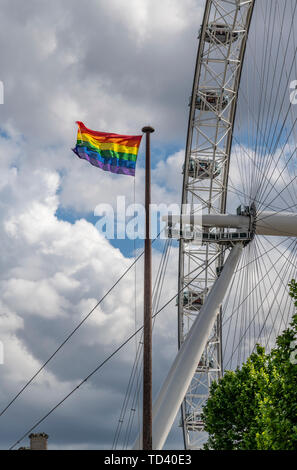 Gay Pride Regenbogen Flagge in London neben dem London Eye - Das Millennium Wheel. Das Rad ist jetzt von Coca Cola gesponsort. Stockfoto