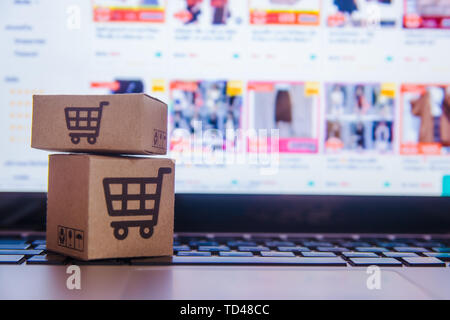 Online Shopping - Papier, Kartons oder Paket mit einem Warenkorb Logo auf einem Laptop Tastatur. Shopping Service auf dem online web und Angebote Home Delivery. Stockfoto