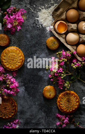 Traditionelle breite Stil Mondkuchen und rosa lila Blüten. Stockfoto