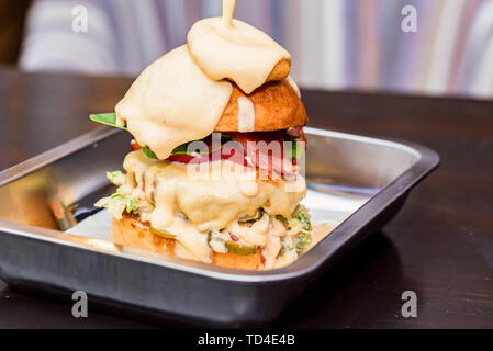 Close up Tall leckere Burger mit geschmolzenem Käse auf dem Tablett serviert. Stockfoto