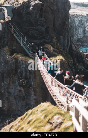 Nordirland, Großbritannien - 8 April 2019: Angst Touristen der gefährlichen, aber wunderschönen Carrick-a-Rede Rope Bridge überqueren Stockfoto